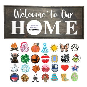 Puede incluir: Un letrero de madera oscura con las palabras "Welcome to Our Home" en letras blancas. Debajo del letrero hay varios imanes decorativos, incluyendo una calabaza, un gato y un corazón. El letrero también dice "Swap the Magnet! 75+ Choices".