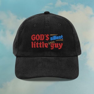 Puede incluir: Gorra de béisbol de pana negra con texto bordado en rojo que dice "GOD'S  silliest little guy" con un halo sobre la "g" de guy.