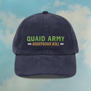 Puede incluir: Gorra de béisbol de pana azul marino con el texto "QUAID ARMY = RIGHTEOUS KILL=" en verde y blanco. La gorra tiene una visera curva y una corona redondeada. El fondo es un cielo azul claro con nubes.