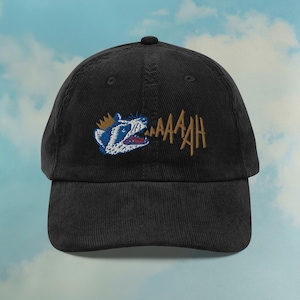 Peut inclure: Une casquette de baseball en velours côtelé noir avec une image brodée d'un animal de dessin animé portant une couronne et criant "AAAAAH".