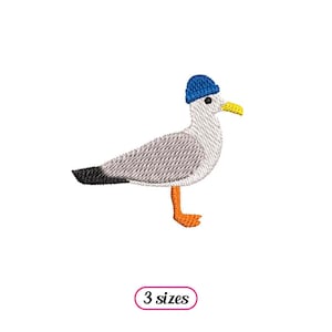 Peut inclure: Broderie représentant une mouette grise portant un bonnet bleu avec un bec et des pattes orange. Le motif est disponible en trois tailles.