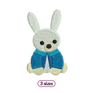 May include: Embroidered design of a white bunny wearing a blue jacket. The bunny is sitting with its ears up and has black eyes. The design is available in 3 sizes.