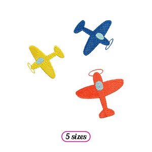 Peut inclure: Trois motifs d'avions brodés en bleu, jaune et rouge. Les avions sont simples et stylisés, avec une hélice et une petite fenêtre. Le texte "5 tailles" est sous les avions.