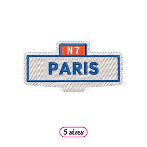Può includere: Toppa ricamata bianca con testo blu che dice "PARIS" e un rettangolo rosso con testo bianco che dice "N7".