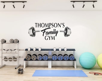 May include: A home gym with a weight rack, dumbbells, a yoga mat, and a wall decal that reads "Thompson's Family Gym" with a barbell and weights.