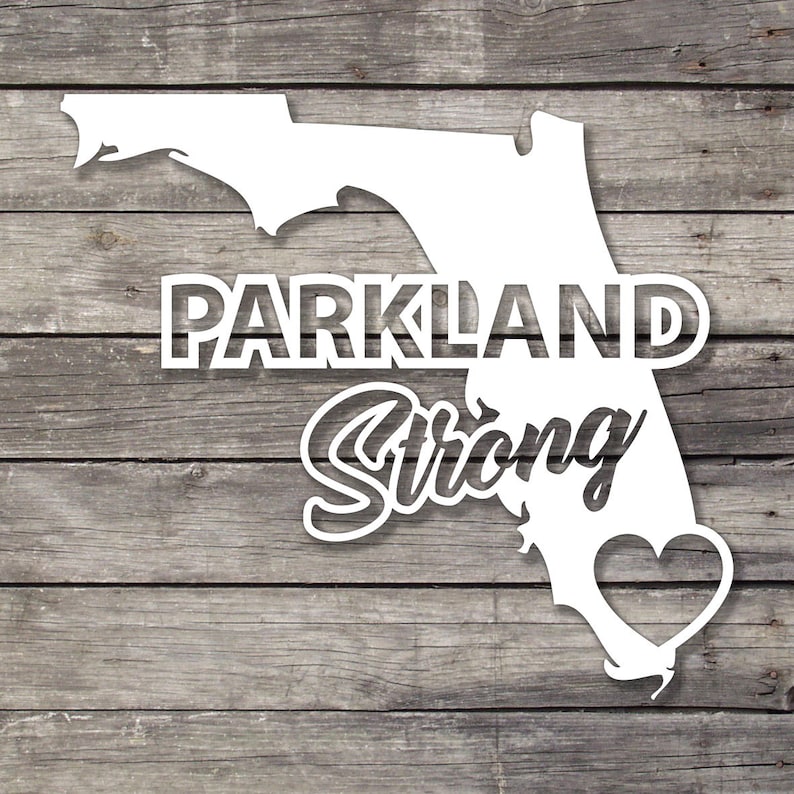 May include: White silhouette of the state of Florida with the words "Parkland Strong" and a heart in the centre. The background is a wood grain texture.