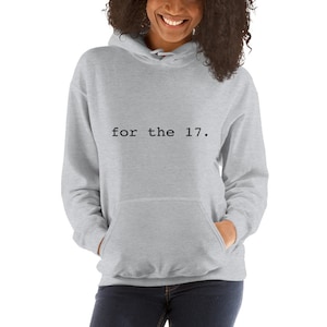 Peut inclure: Un sweat à capuche gris chiné avec le texte "for the 17." imprimé en noir.
