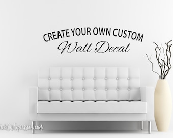 May include: A white tufted sofa is positioned below the text "CREATE YOUR OWN CUSTOM Wall Decal" in black script. A tall, cream-colored vase with dark branches sits to the right, creating a minimalist, modern aesthetic.