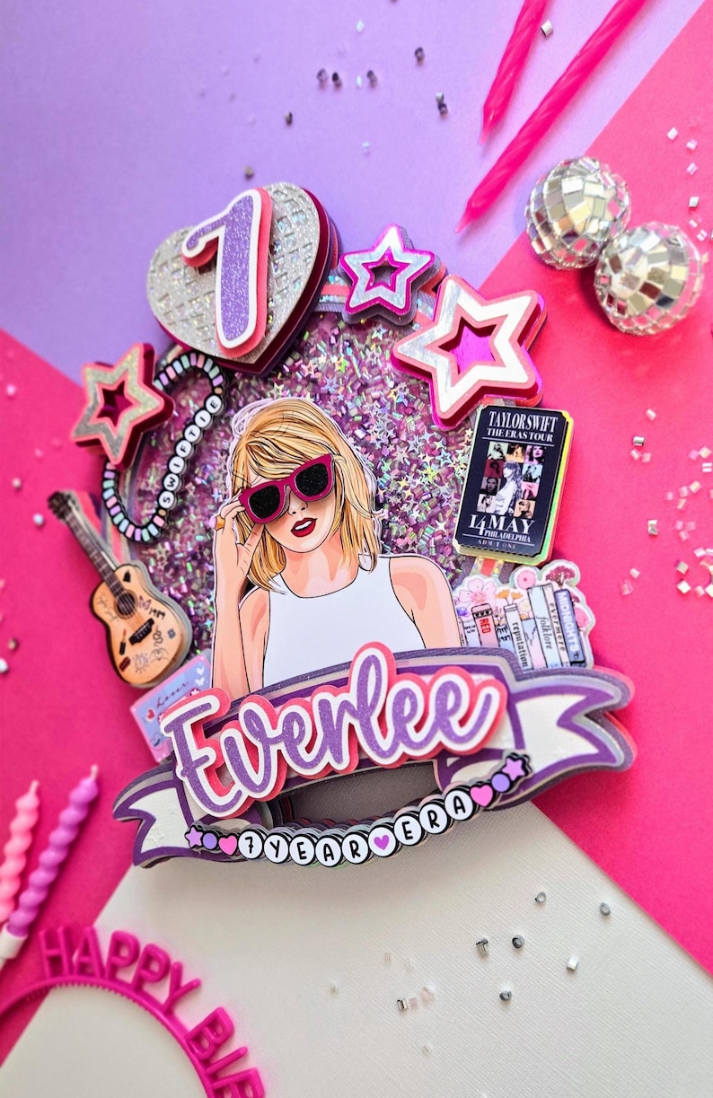 May include: A colorful birthday cake topper featuring a cartoon illustration of a woman wearing sunglasses. The topper includes stars, a guitar, and the text "Everlee 7 Year Era". Pink and purple accents with glitter.