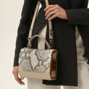 May include: A beige and gray snakeskin handbag with a wooden handle and a brown leather trim. The bag has a top flap closure and a shoulder strap.