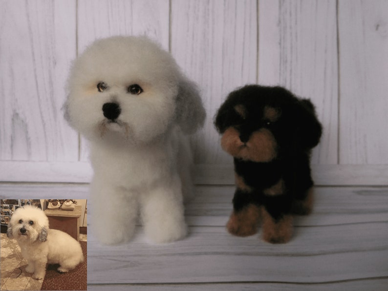 K&ouml;nnte beinhalten: Zwei Filz-Hundefiguren, eine wei&szlig;e mit grauen Ohren und eine schwarze mit braunen Akzenten. Die Figuren stehen auf einer wei&szlig;en Holzoberfl&auml;che.