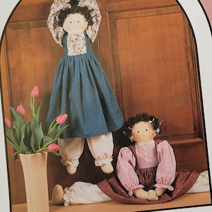 May include: A pink and white sewing pattern booklet with the title "Dream Spinners" and the number "#134 Warm at Heart". The pattern is for a 28-inch doorknob/draft stopper doll with adjustable length. The pattern is from Great American Quilt Factory, Inc., 1987.