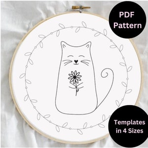 May include: Black and white line art embroidery pattern of a cat holding a flower in a wreath of leaves. PDF pattern, templates in 4 sizes.