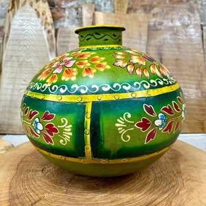 May include: A green, round, hand-painted ceramic vase with floral designs in shades of red, orange, yellow, and blue. The vase has a yellow rim and gold accents.