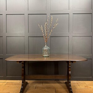 May include: A dark brown wooden table with a rectangular top and decorative legs. A clear glass vase with branches is centered on the table. The table is approximately 152 cm long.