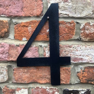 May include: Black metal house number four attached to a brick wall.
