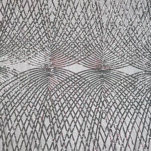 Op de afbeelding: Zilveren en rode paillettenstof met een geometrisch patroon. De stof heeft een mesh-rug.