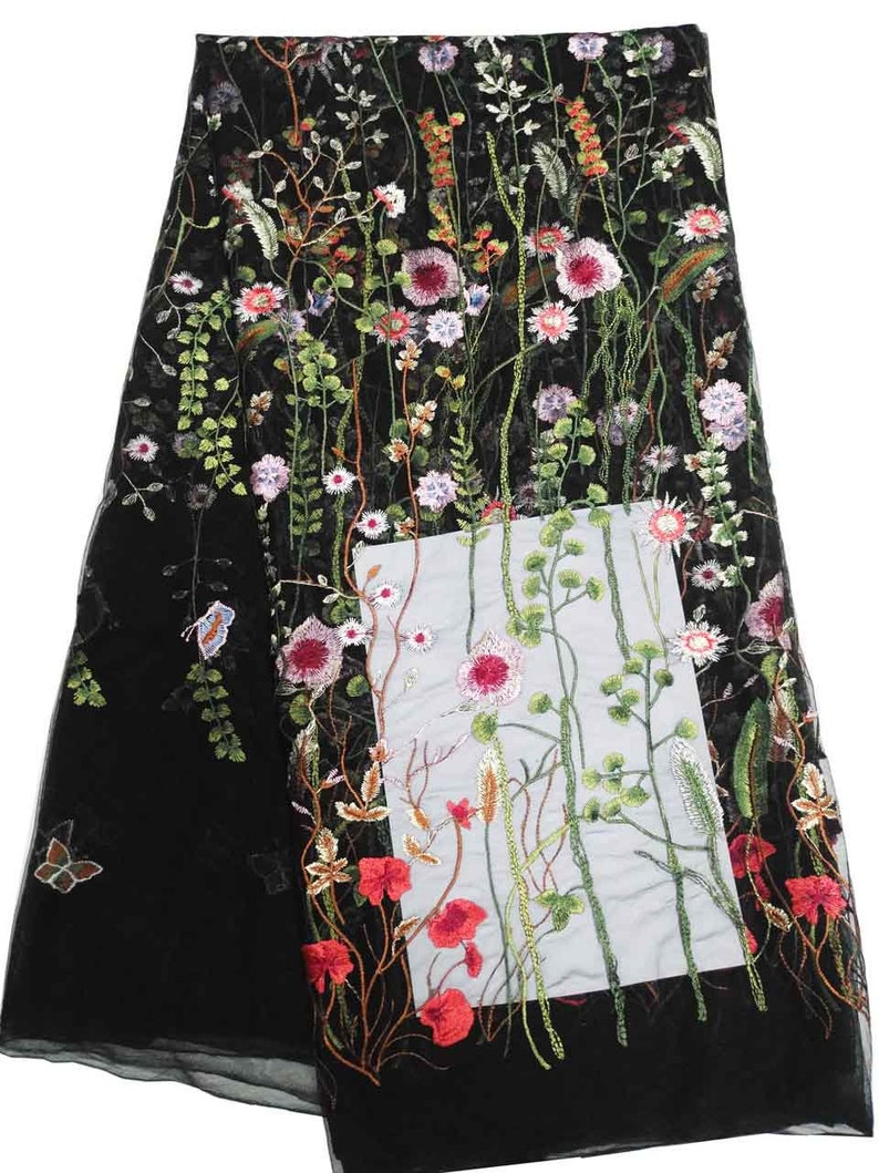 K&ouml;nnte beinhalten: Schwarzer Stoff mit floralem Stickmuster. Die Stickerei zeigt rote, rosa, wei&szlig;e und gr&uuml;ne Blumen sowie Schmetterlinge. Geeignet f&uuml;r Kleidung oder Heimtextilien.