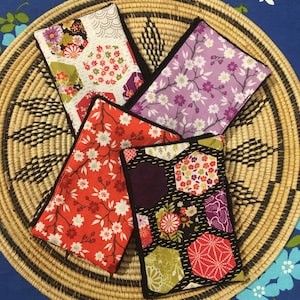 Pode incluir: Quatro pequenas bolsas de tecido com diferentes padrões florais. As bolsas estão alinhadas em círculo em uma cesta de vime.