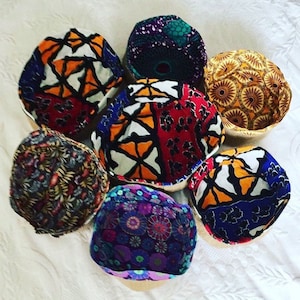 Puede incluir: Un conjunto de siete cestas de tela coloridas con una variedad de patrones geométricos y florales. Las cestas están hechas de materiales naturales y tienen un aspecto rústico y hecho a mano.