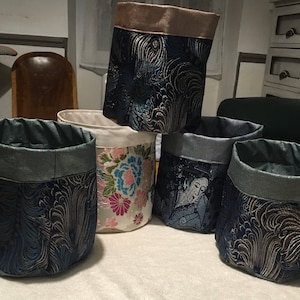 Può includere: Quattro cesti di stoffa per la conservazione con motivi diversi. I cesti sono blu, bianchi e grigi con accenti dorati. I motivi includono fiori, onde e una donna giapponese.