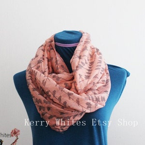 May include: A peach-colored infinity scarf with a gray leaf pattern is draped on a blue mannequin. The scarf is made of a lightweight fabric. The text "Kerry Whites Etsy Shop" is visible.
