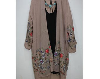 May include: A long, light brown kimono with floral embroidery in shades of red, blue, and green. The kimono has a V-neck and long sleeves.