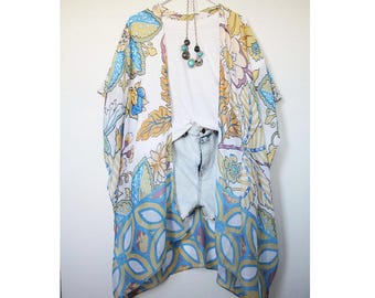 May include: A white sheer kimono with a floral and geometric pattern in shades of blue, yellow, and pink. The kimono has a loose fit and is perfect for layering over a simple top or dress.
