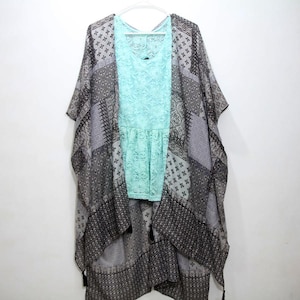 May include: A gray and black patterned kimono with a light blue lace top underneath. The kimono has a long, flowing design and features tassels at the bottom.