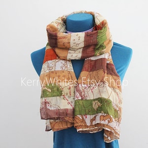 Puede incluir: Bufanda ligera con diseño de mapa en tonos marrón, naranja, verde y crema. La bufanda está drapeada sobre un maniquí azul. El texto "Kerry Whites Etsy Shop" es visible.