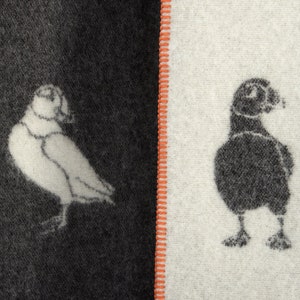 以下が含まれることがあります： 黒と白の布地に、左側に白い鳥、右側に黒い鳥が描かれています。布地は赤い縫い目で半分に分けられています。