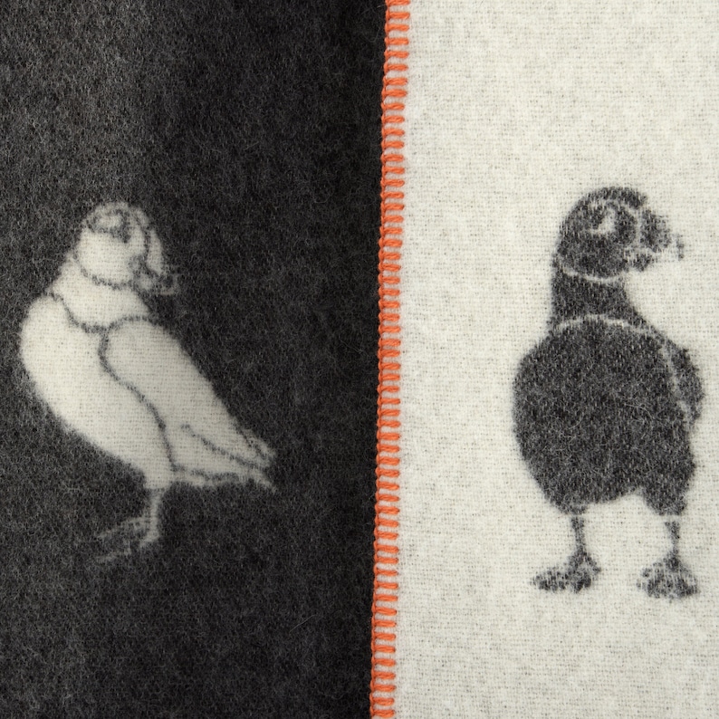以下が含まれることがあります： 黒と白の布地に、左側に白い鳥、右側に黒い鳥が描かれています。布地は赤い縫い目で半分に分けられています。