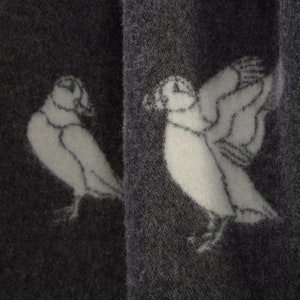 以下が含まれることがあります： 濃いグレーの生地に、白いスタイリッシュなデザインで2羽のツノメドリが描かれています。ツノメドリは反対方向を向いており、シンプルでミニマルなデザインです。