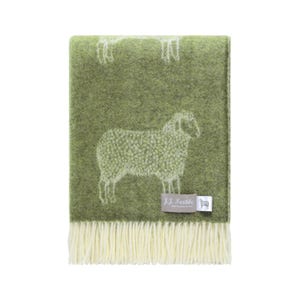 May include: A green wool throw blanket with a sheep pattern. The blanket has a fringe at the bottom and a tag that reads "J.J. Textile". The sheep are white and the blanket is a solid green color.