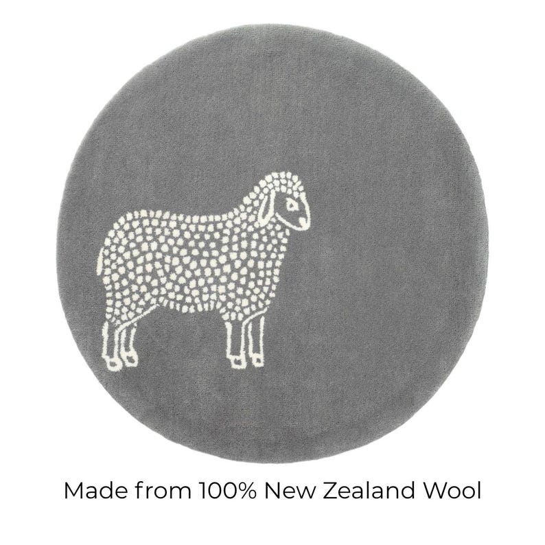 May include: A round, gray rug featuring a white sheep design. The sheep is depicted in a simple, dotted style. The text at the bottom reads "Made from 100% New Zealand Wool."