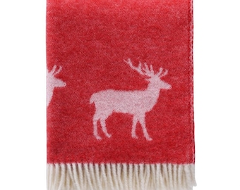 May include: Red throw blanket with a white deer pattern and a white fringe border.