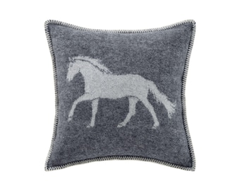 May include: A square, gray decorative pillow featuring a white horse silhouette. The pillow has a textured appearance and a contrasting white stitched border. The horse is depicted in a running pose, adding a touch of equestrian style.