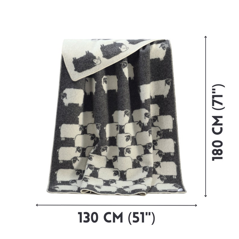 May include: A black and white sheep patterned throw blanket made of wool. The blanket is 130 cm wide and 180 cm long.