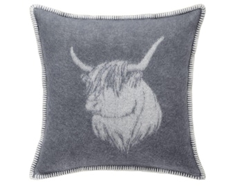 May include: A square, gray decorative pillow featuring a Highland cow design. The cow's head is in a lighter gray, with long horns and shaggy fur. The pillow has a white stitched border.