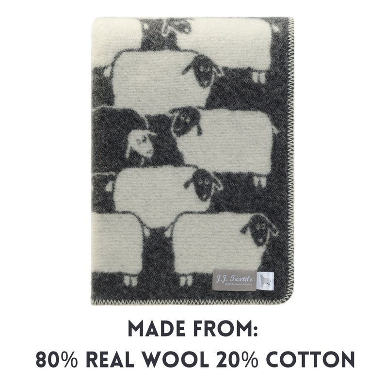 May include: A white and grey wool throw blanket with a repeating pattern of black and white sheep. The blanket has a label that reads "J-J. Textile" and "Made from: 80% Real Wool 20% Cotton".