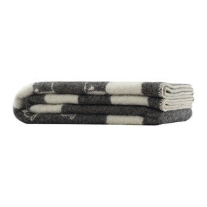 May include: A folded grey and white striped wool blanket with a subtle pattern.