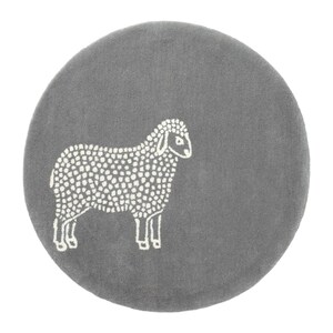 May include: A round, gray rug featuring a white sheep design. The sheep is depicted in a simple, dotted style, standing on all fours. The rug has a soft, plush texture, suitable for a child's room or nursery.
