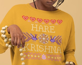 May include: A mustard yellow sweatshirt with a colourful embroidered design featuring the text "Hare Krishna" and peacocks. The design also includes hearts, flowers, and geometric patterns.