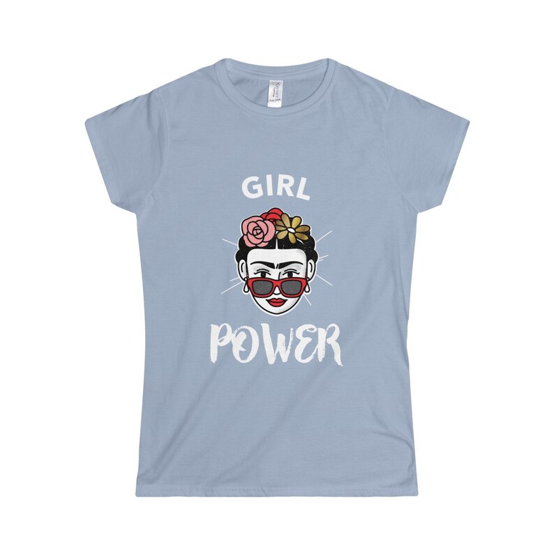 May include: Light blue t-shirt with a white graphic of a woman with flowers in her hair and sunglasses. The text "GIRL POWER" is printed below the image.
