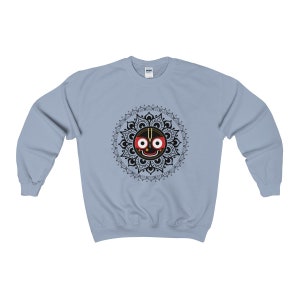 May include: A light blue sweatshirt with a black and white mandala design featuring a black face with red eyes and a third eye in the centre.
