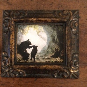 May include: A framed print of a black bear and two cubs in a cave setting. The bears are silhouetted against a light background.