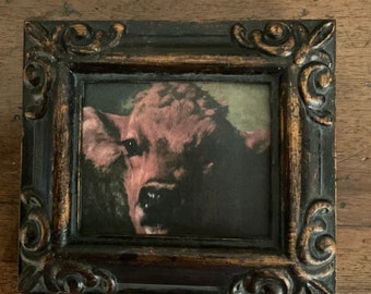 May include: A framed painting of a red cow with a dark background. The frame is black with gold accents.