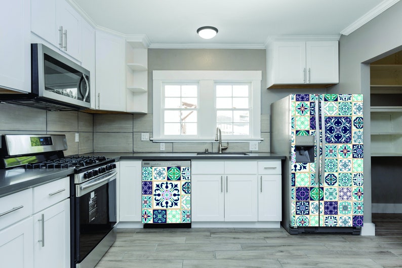 May include: A white kitchen with a stainless steel stove, microwave, and dishwasher. The refrigerator has a decorative tile design on the front.