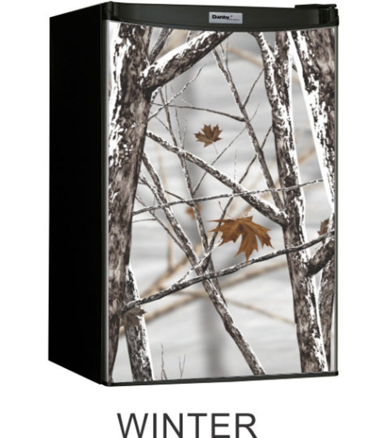 May include: A black mini fridge with a white and brown camouflage design featuring a winter scene with trees and leaves. The fridge has the word "Danby" on the top.