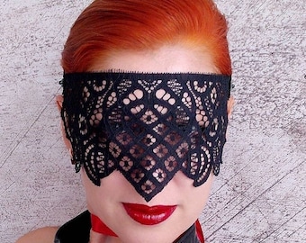 May include: A black lace eye mask with a delicate floral pattern. The mask covers the eyes and extends to the bridge of the nose.